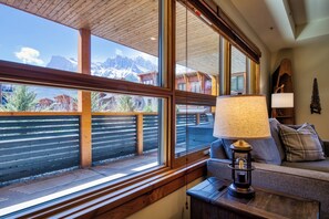 A room with large windows, a wooden ceiling, a sofa, a lamp, and a view of mountains. - Panoramic Views - 3 Bedrooms in White Spruce Lodge (Canmore)