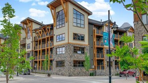 A multi-story building with a stone facade, large windows, and wooden accents. - Panoramic Views - 3 Bedrooms in White Spruce Lodge (Canmore)