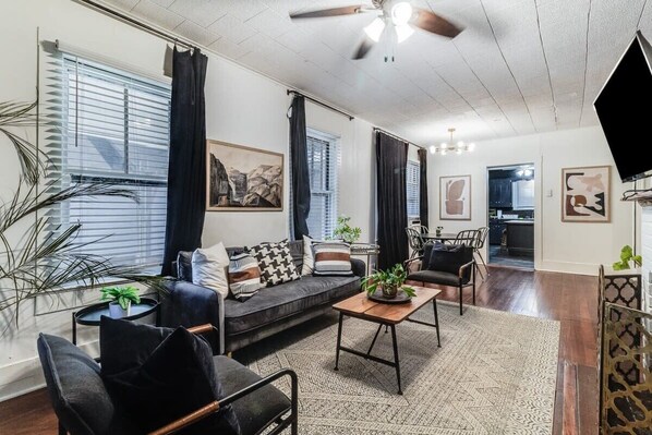 A modern living room with a sofa, chairs, a coffee table, and artwork on the walls.