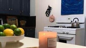 A kitchen with a wooden cutting board, a lit candle, and a bowl of fruit. - 4BR Downtown Lafayette-Garden, Parking, Walk to Arts District (Lafayette)