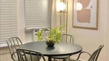 Una mesa de comedor redonda con seis sillas, una planta en maceta y un moderno candelabro arriba.