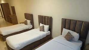 Three single beds with wooden headboards and white bedding in a hotel room. - Rayan Hotel Suites (Amman)