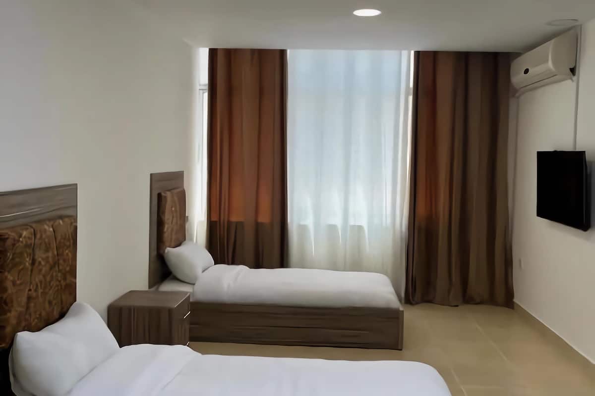 Ein Hotelzimmer mit zwei Betten, einem Flachbildfernseher und einer Klimaanlage.