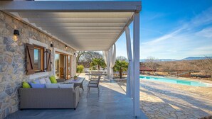 Un espace extérieur abrité, doté de murs en pierre, d’une piscine et de mobilier d’extérieur.