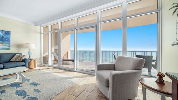 A spacious living room with a large sliding glass door leading to a balcony with a view of the sea. - Beachfront 3BR with water slide!  New to the Rental Market!! (Gulf Shores)