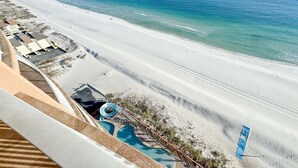 A beach view with a pool area and a building with a sloped roof. - Beachfront 3BR with water slide!  New to the Rental Market!! (Gulf Shores)