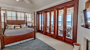 Een slaapkamer met een groot bed, een houten garderobe en uitzicht op zee.