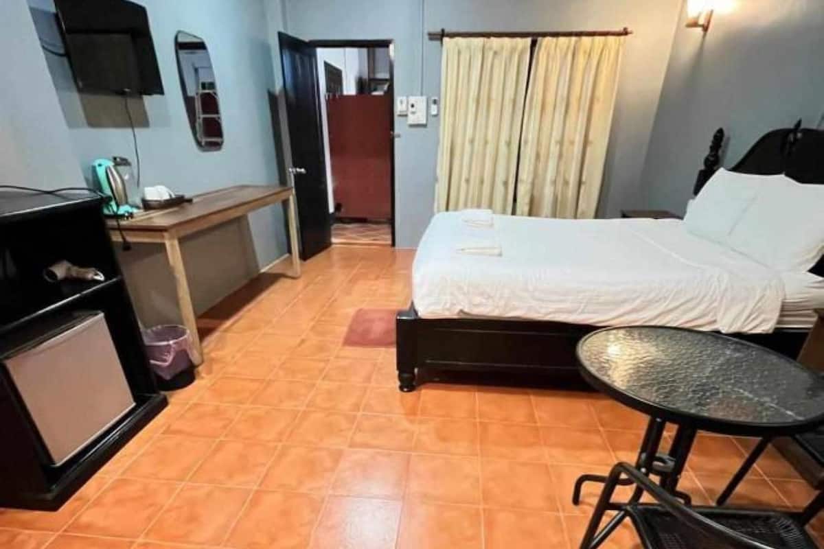 A compact hotel room with a bed, a small desk, a chair, and a table.