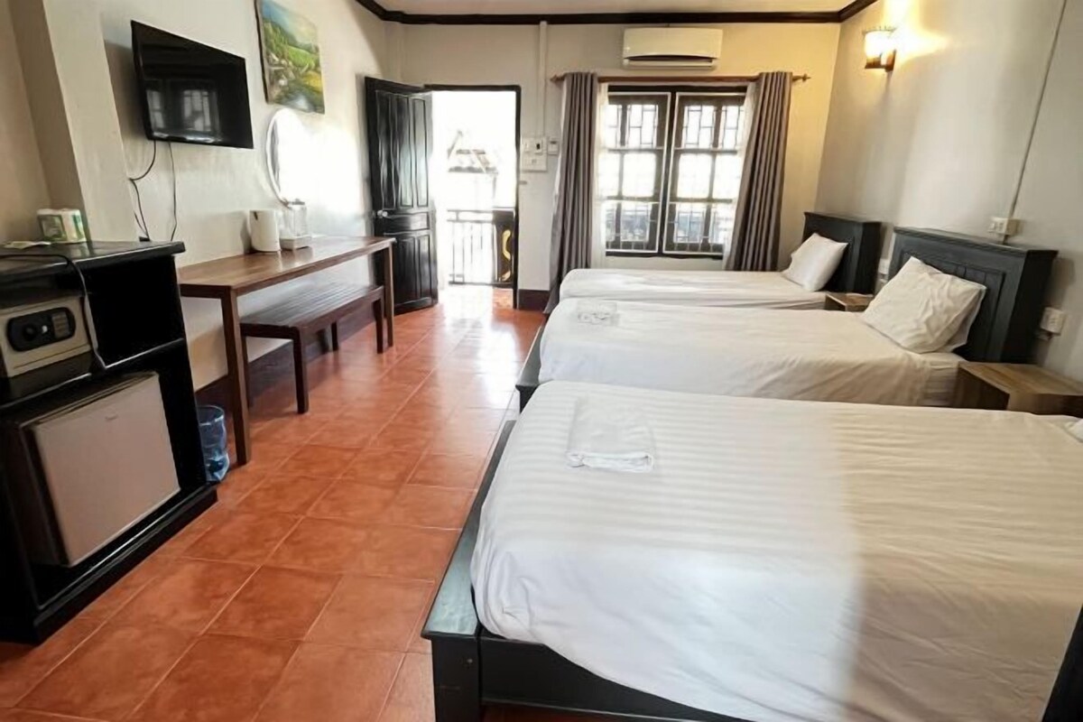 A hotel room with two beds, a desk, a television, and a window with curtains.