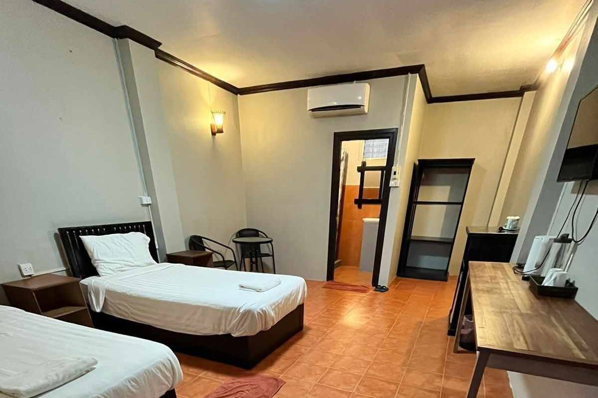 A hotel room with two beds, a small table, a chair, and a bathroom visible through an open door.
