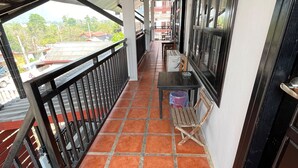 Un balcon abrité avec un sol carrelé, une table et un banc.