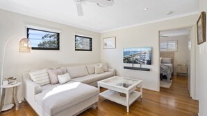 A modern living room with a sofa, coffee table, and artwork on the walls. - Your Island Paradise Awaits! (Point Lookout)