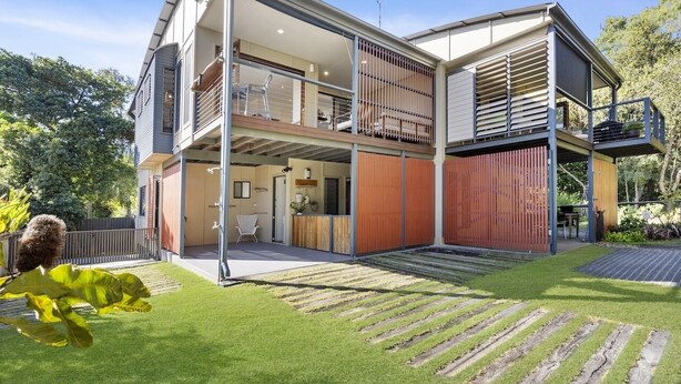 A modern two-story house with a balcony, a wooden deck, and a well-maintained lawn. - Your Island Paradise Awaits! (Point Lookout)