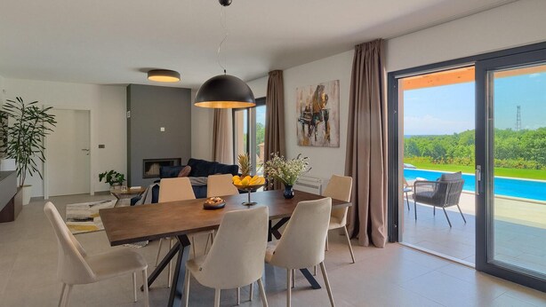 Un comedor moderno con una mesa de madera, sillas blancas y una lámpara colgante grande.