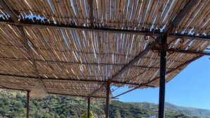 Une terrasse extérieure avec des tables et des chaises, offrant une vue sur un paysage vallonné.