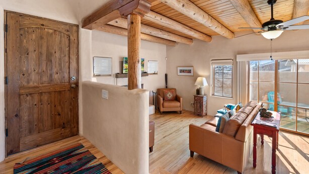 Amplia sala de estar con techo de madera, una puerta grande de madera, un sofá y una mesa.