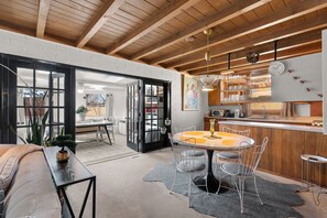 Una cocina moderna con una mesa de comedor redonda, sillas blancas y techo de madera.