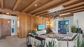 Ein geräumiges Wohnzimmer mit Holzbalken, einem großen Fernseher und einer gemütlichen Sitzecke.