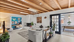 Ein modernes Wohnzimmer mit Kamin, einem weißen Sofa und einem Essbereich mit Tisch und Stühlen.