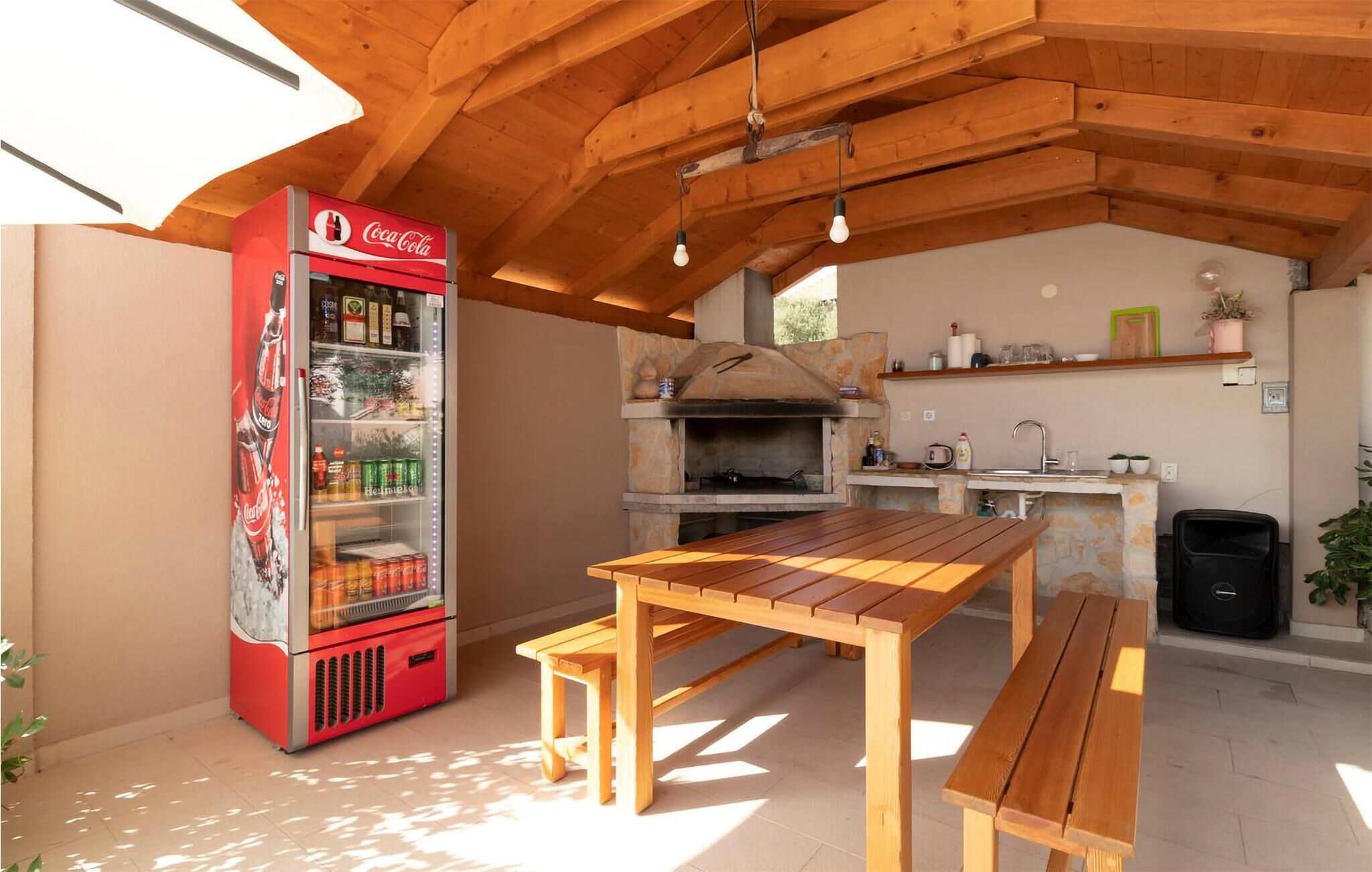 A kitchen with a stone oven, wooden table, and a Coca-Cola refrigerator.