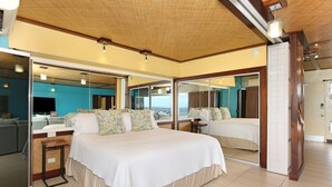 Een ruime slaapkamer met een groot bed, een klein tafeltje en uitzicht door een glazen deur.
