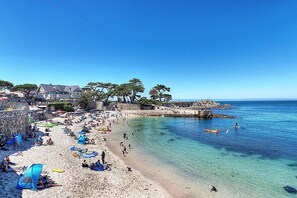 Una playa con aguas cristalinas, sombrillas y gente.