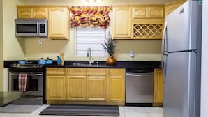 A kitchen with wooden cabinets, a microwave, stove, sink, and a refrigerator. -  Sweet Kensville (Kingston)