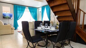 A dining area with a table set for four, black chairs, and a TV mounted on the wall. -  Sweet Kensville (Kingston)