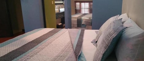 A bedroom with a bed, pillows, and a bathroom visible through an open door.