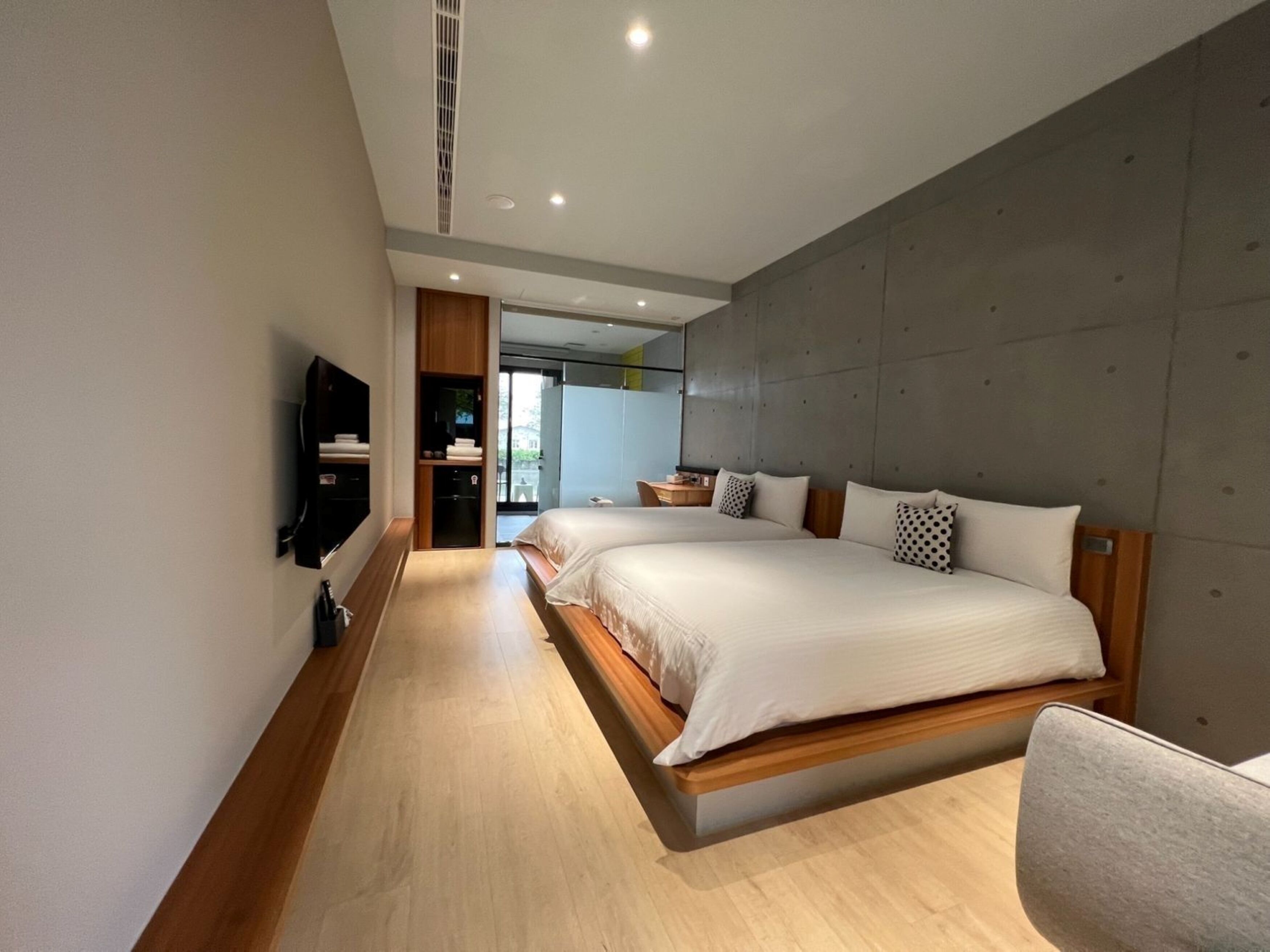 A modern bedroom with two beds, a flat-screen TV, and a large mirror.
