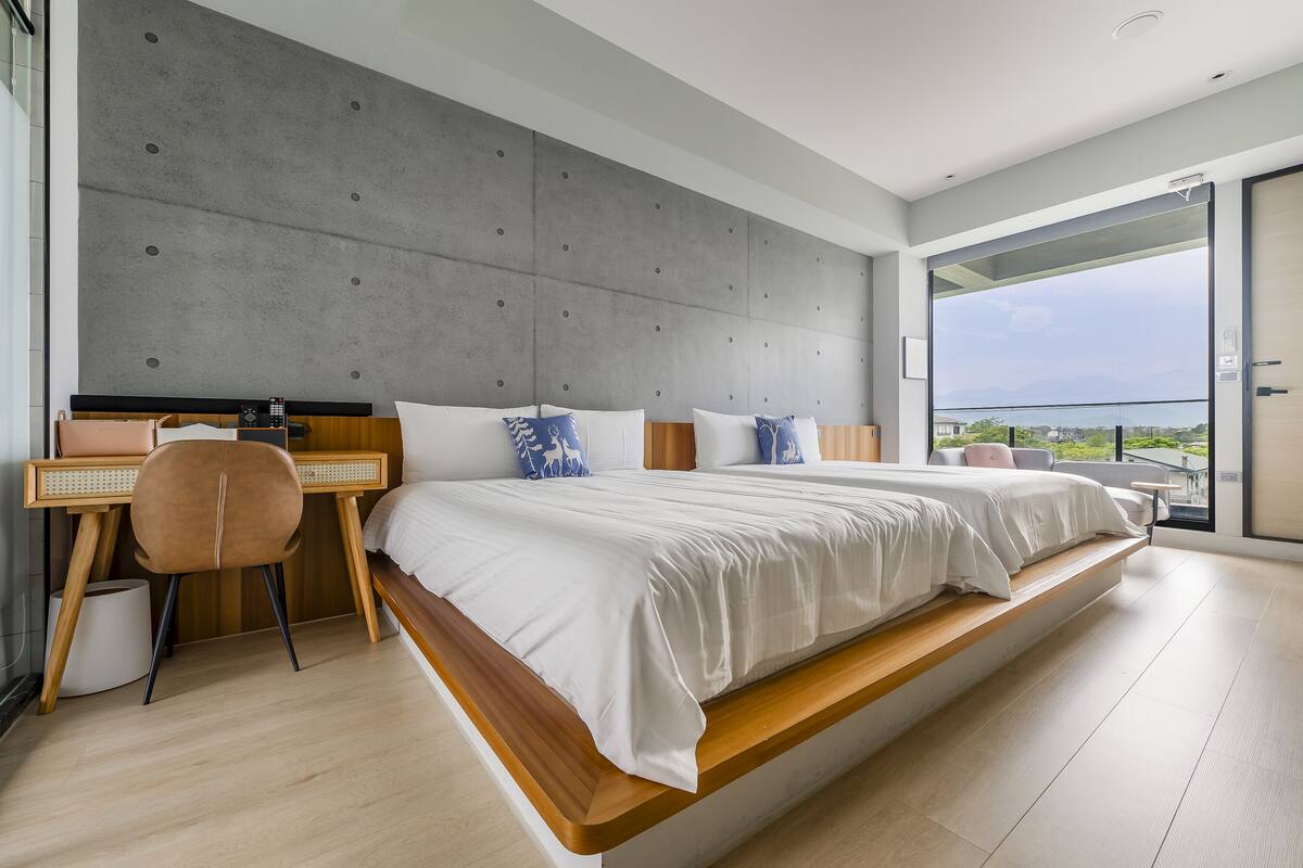A modern bedroom with a large bed, a desk, and a chair.