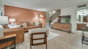 Ein modernes Wohnzimmer mit einem braunen Sofa, einem Holztisch und einer Treppe, die in den oberen Stock führt.
