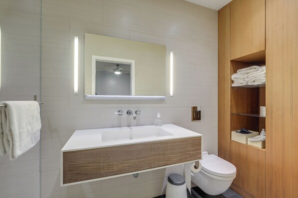 A modern bathroom with a large sink, mirror, and wooden vanity.