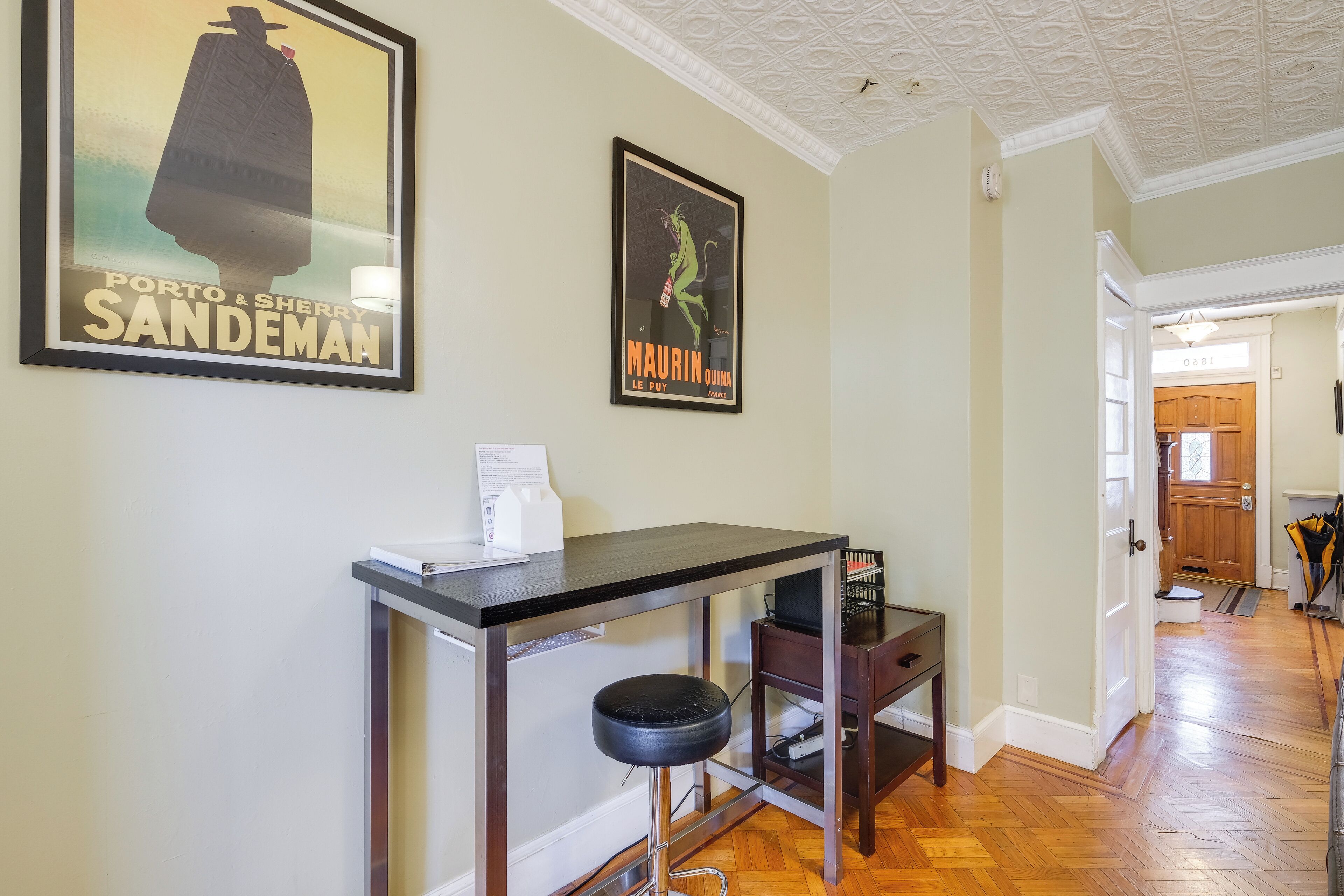 A hallway with a bar area, a poster on the wall, and a door leading to another room.