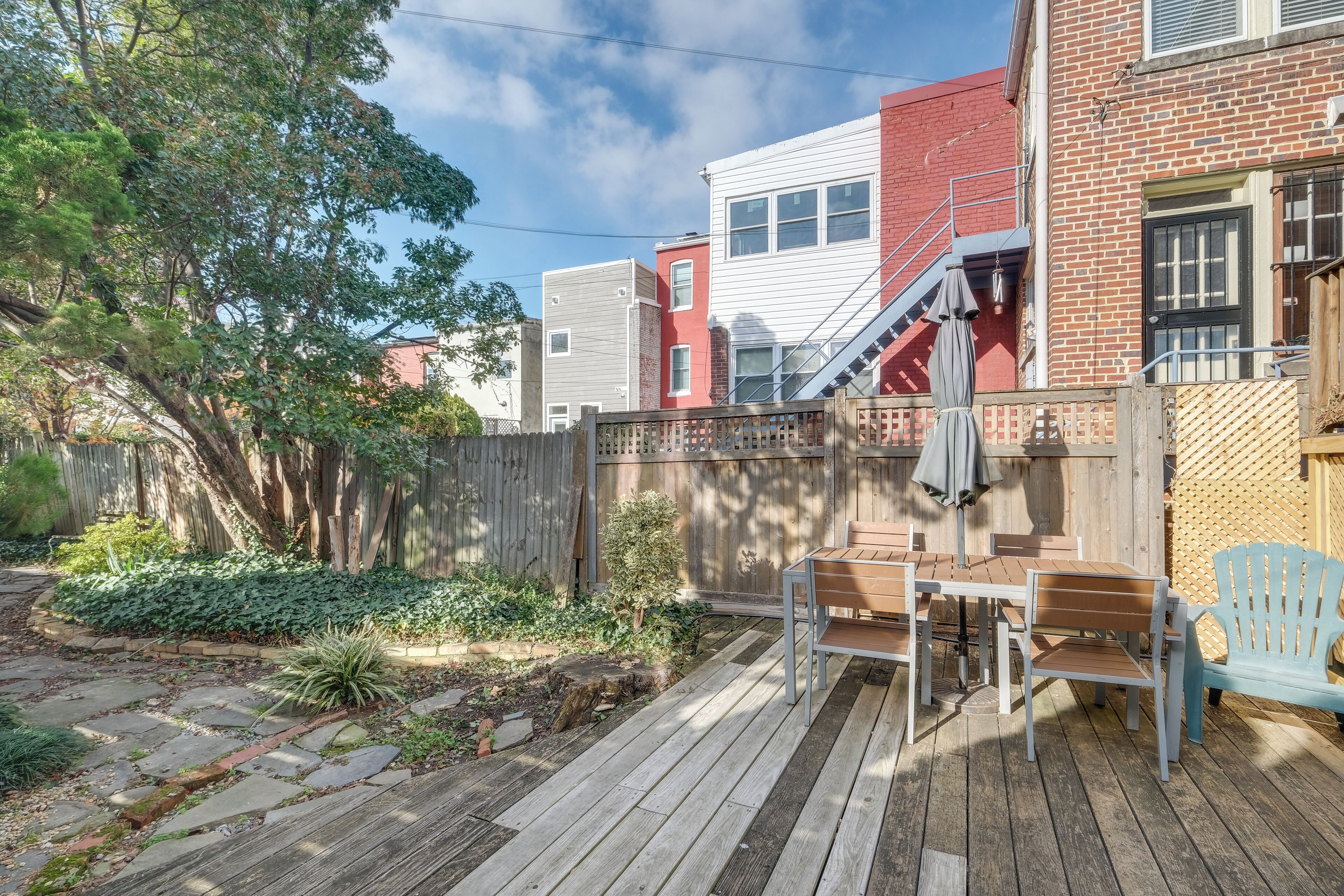 A wooden deck with outdoor furniture, a brick building, and a wooden fence.