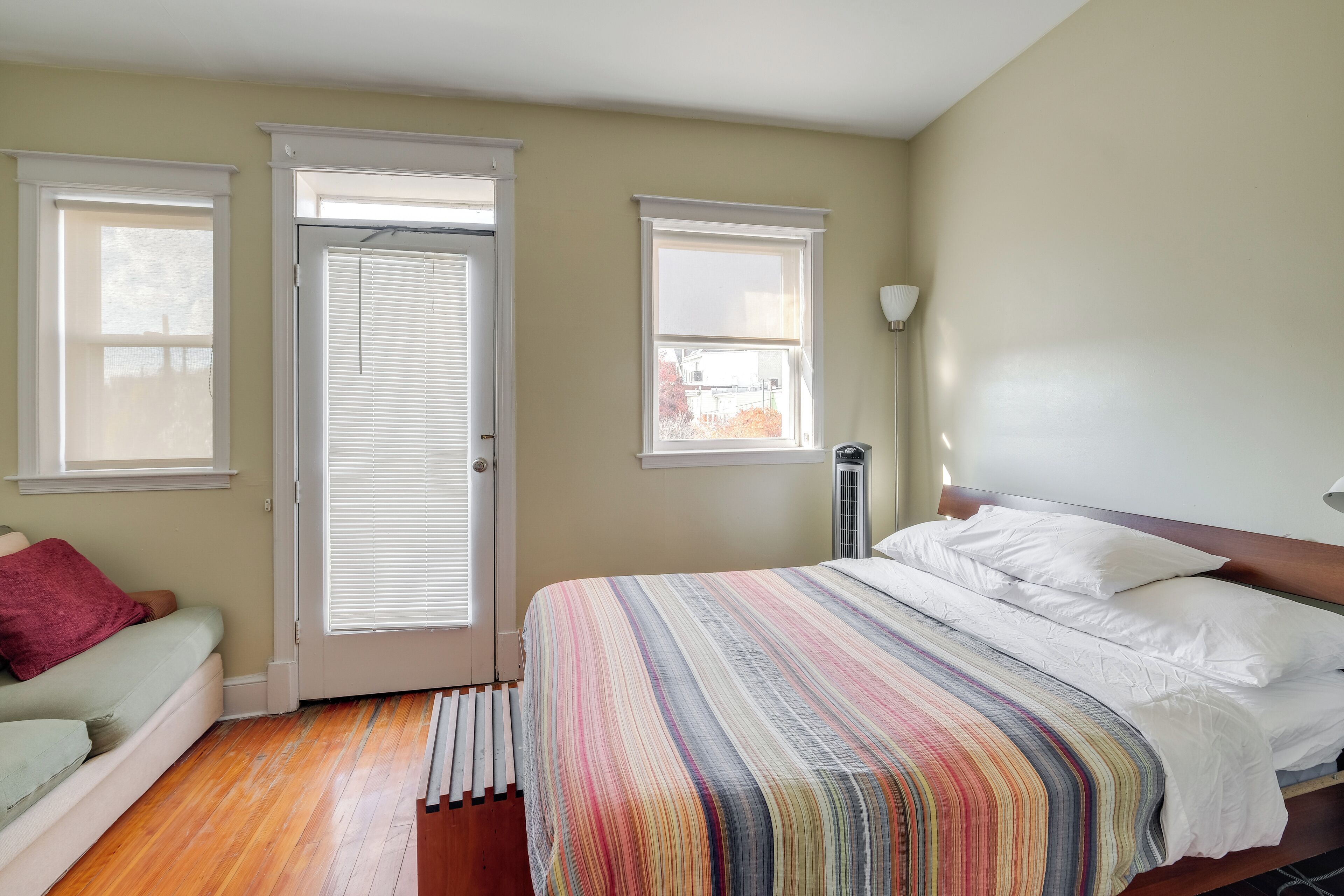 A bedroom with a bed, a window, a radiator, and a door.