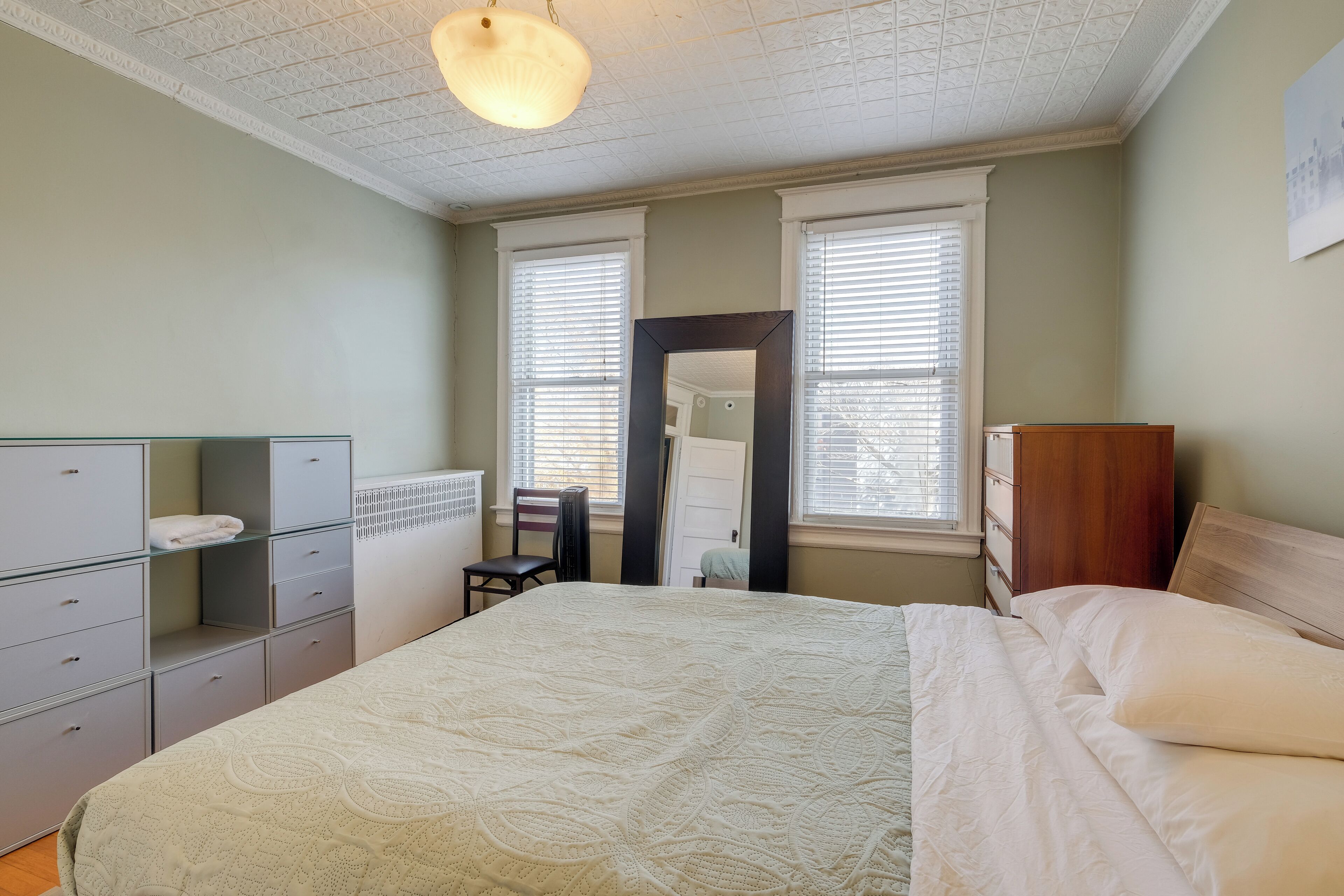 Ein Schlafzimmer mit einem großen Bett, einem Schminktisch, einem Sessel und einem Spiegel.