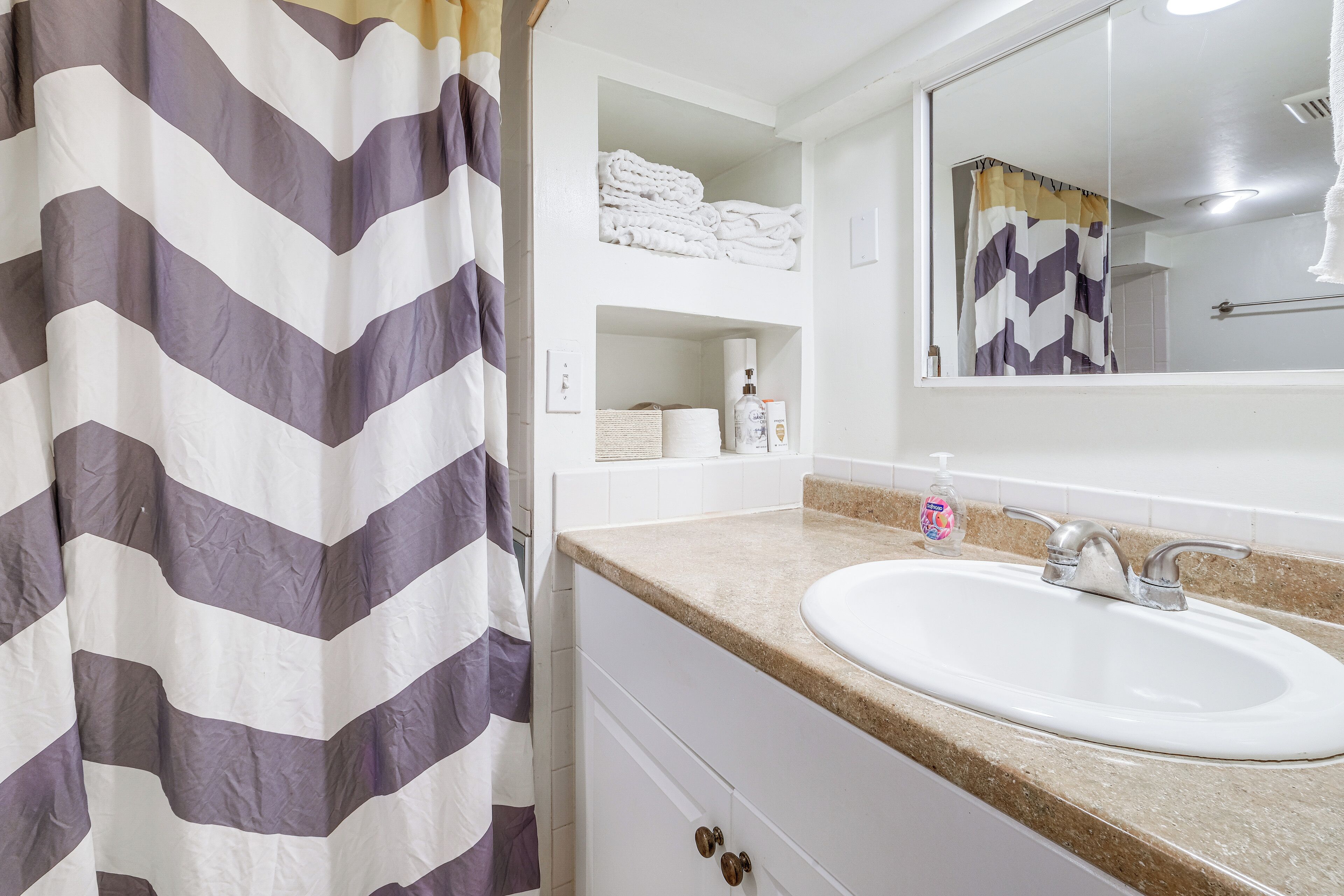 A bathroom with a white sink, a mirror, and a towel rack.