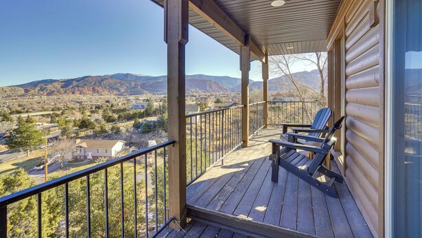 A wooden deck with a view of mountains and a house in the background.