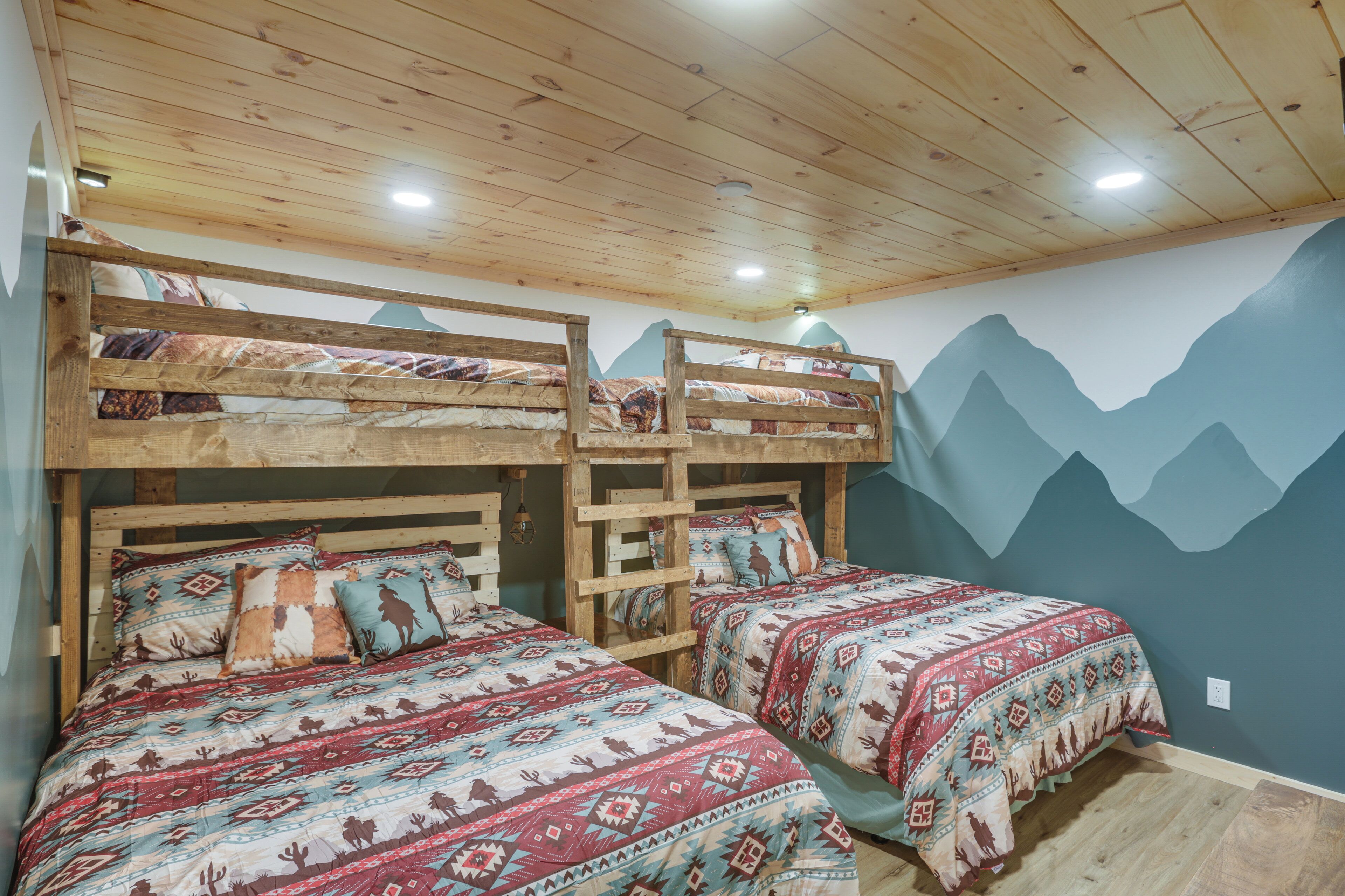 A room with two bunk beds and two single beds, wooden ceiling, and mountain-themed wall art.