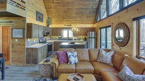 Ein gemütliches Blockhaushaus-Interieur mit Holzvertäfelung, einem großzügigen Wohnbereich mit Ledersofa und einer Küche mit modernen Geräten.