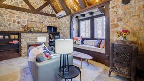 Une pièce chaleureuse avec des murs en pierre, un plafond en bois, un canapé, une table et un buffet.