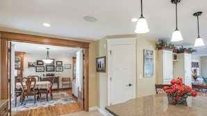A kitchen with granite countertops, wooden chairs, and a dining area with a floral rug.
