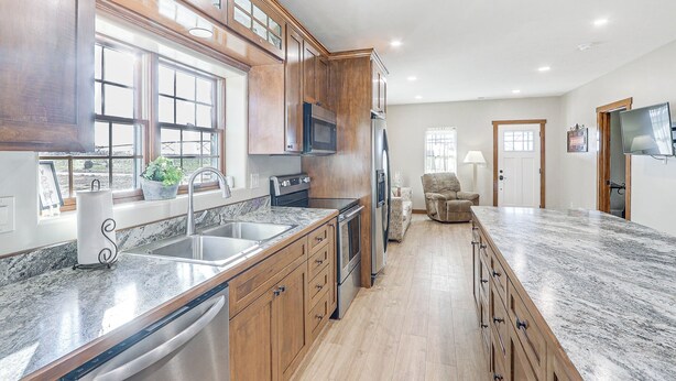 Une cuisine moderne avec des meubles en bois, un réfrigérateur en acier inoxydable et un grand îlot central doté d’un comptoir en granit.
