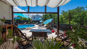 Un espace aménagé au bord de la piscine, avec des chaises longues, une table et des parasols.