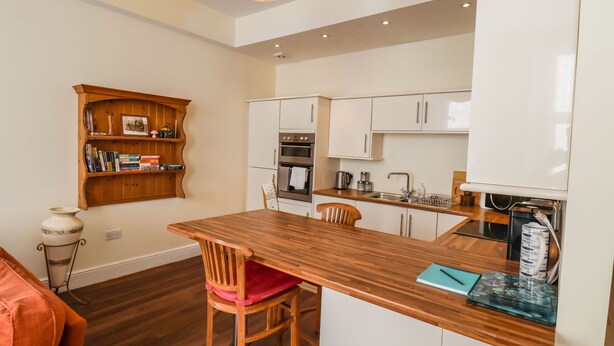 Una cocina moderna con armarios blancos, una isla de madera y un horno empotrado.