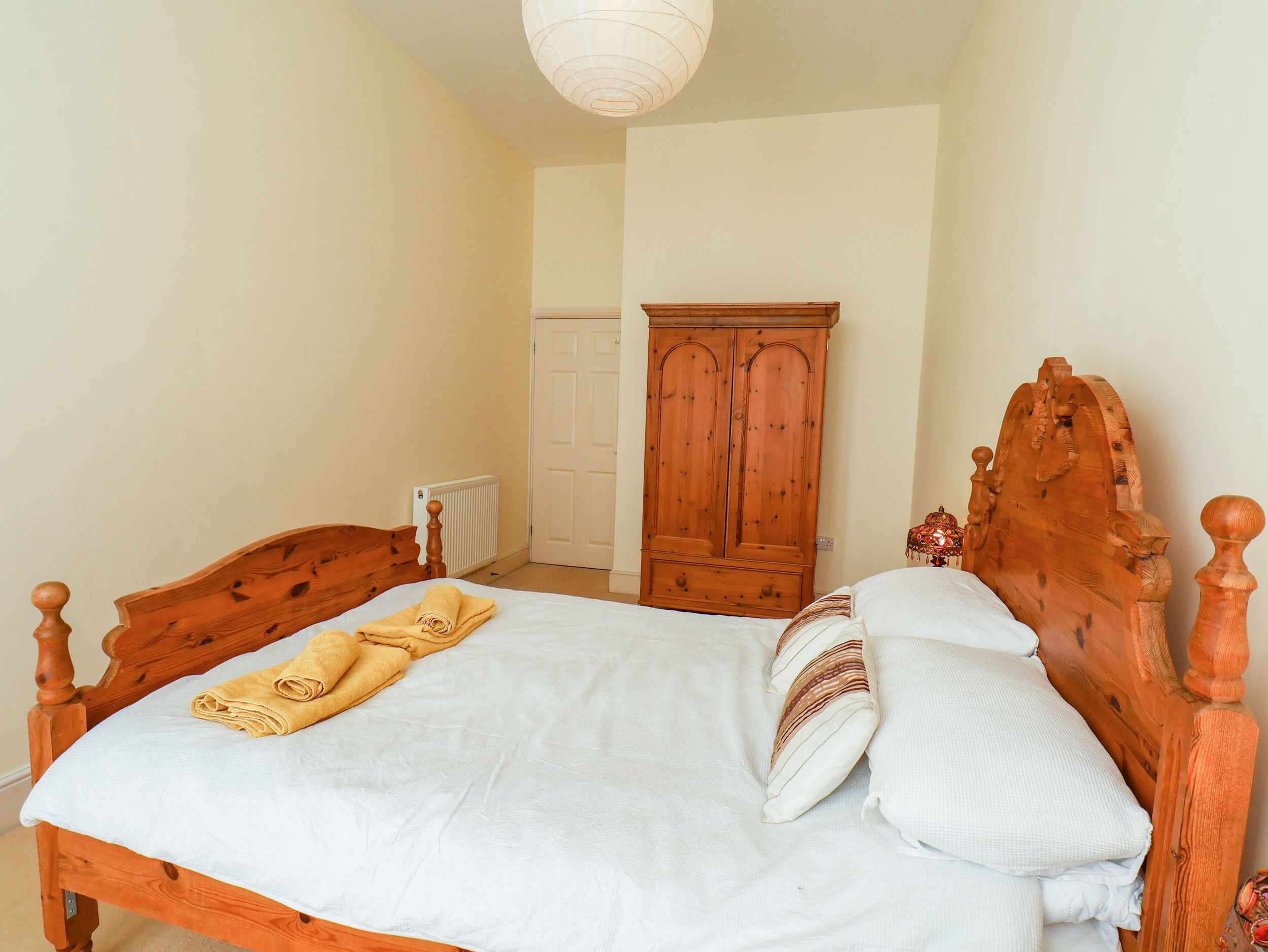 Een slaapkamer met een houten bed, een witte dekbedovertrek en een opgerolde handdoek.
