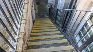 Un escalier avec des rampes en métal et des marches en pierre menant à l’entrée d’un bâtiment.