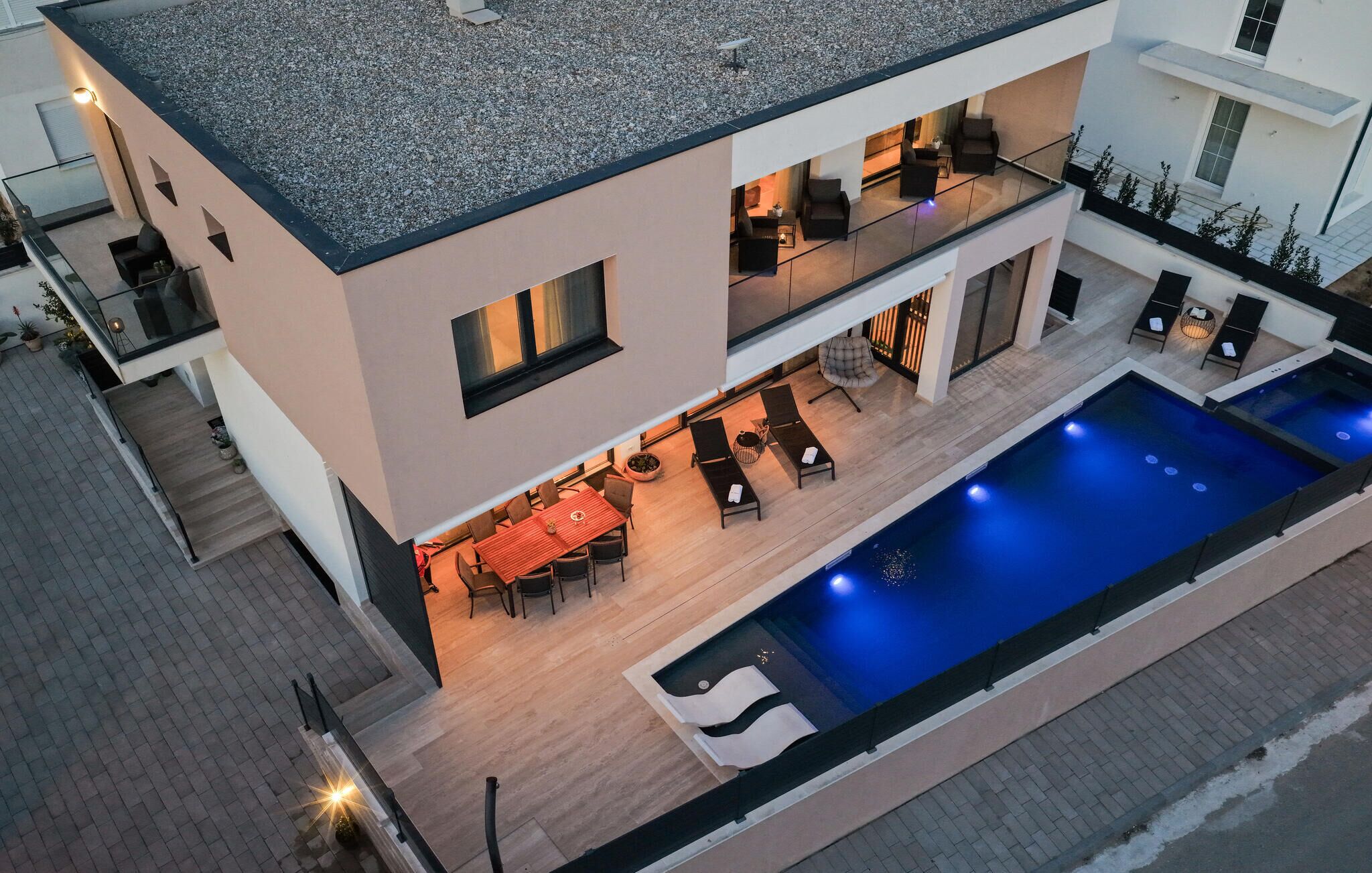 Een moderne, twee verdiepingen tellende woning met een zwembad, buitenmeubilair en een balkon.