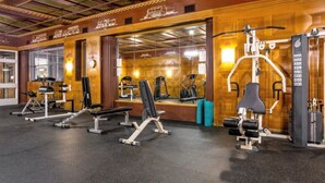 Une salle de sport équipée de divers appareils d’exercice, notamment des tapis de course, des appareils de musculation et un banc.